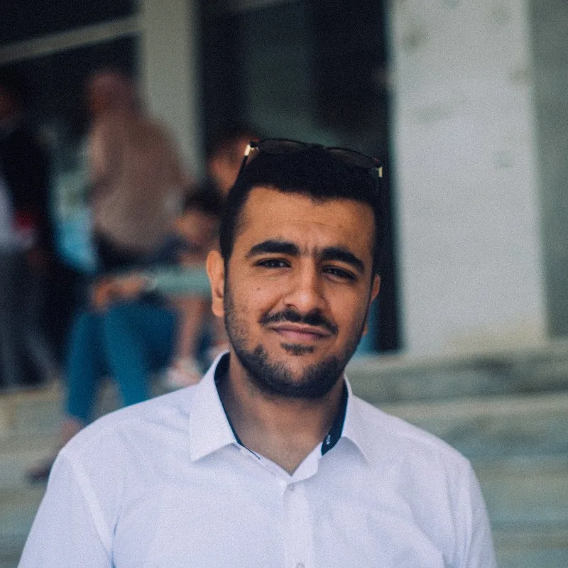 Nizar in a white shirt, standing on steps outdoors